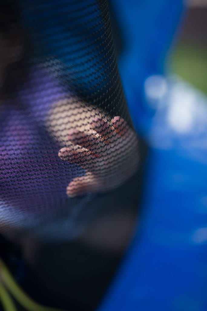 A hand resting safely against a trampoline safety net — a reliability safety layer